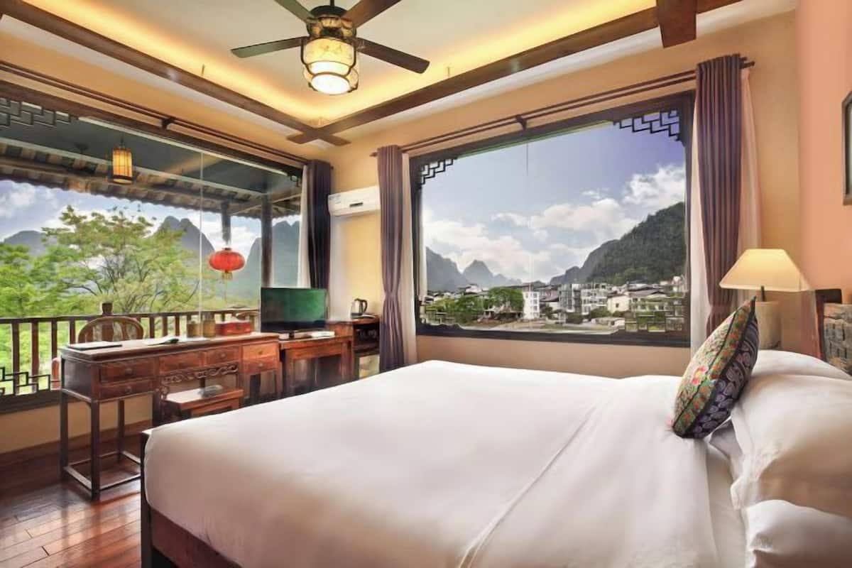Une chambre d’hôtel équipée d’un lit, d’un bureau, d’une chaise, d’une télévision et offrant une vue sur les montagnes et la ville.