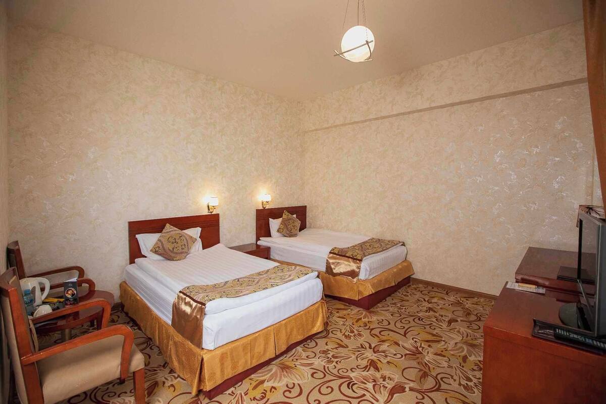 Una habitación de hotel con dos camas, un escritorio, una silla y un televisor.