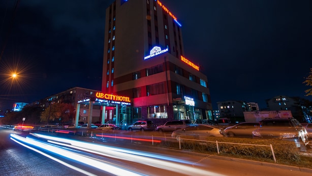 Un hotel a più piani con insegne che riportano "UB CITY HOTEL" e il ristorante "MONITOR BAATANI".