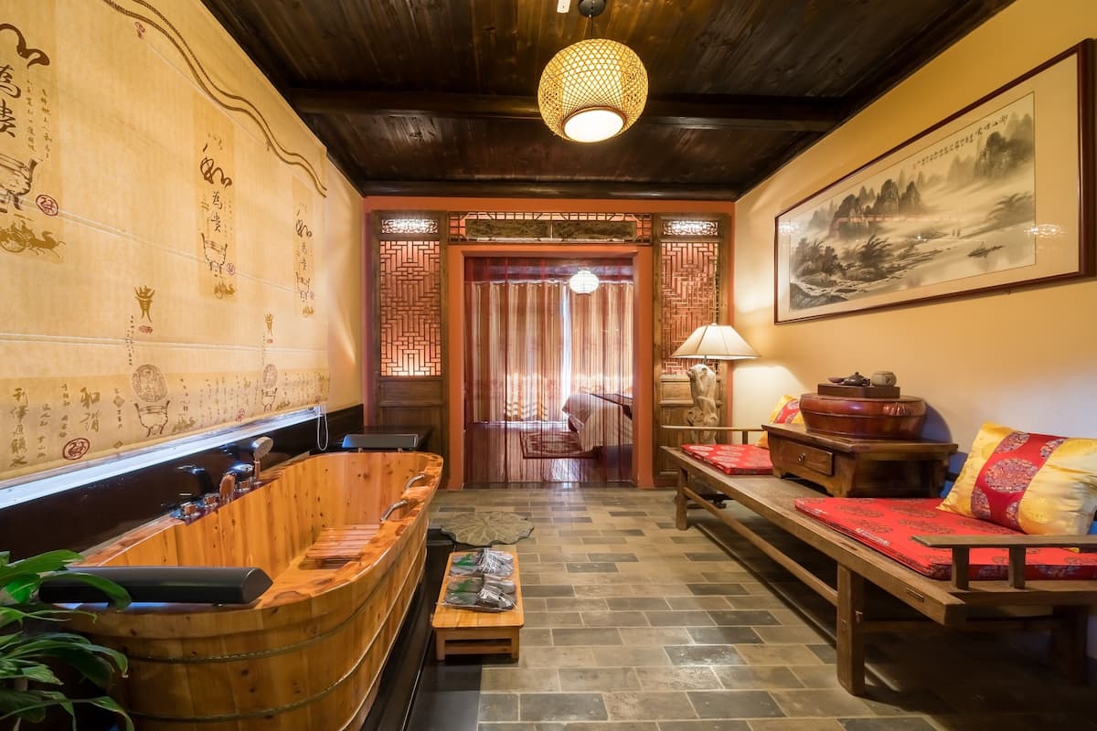 A traditional interior with a wooden bar, a sofa with red cushions, and a large painting on the wall.