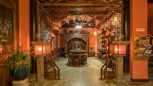 Ein traditionelles Interieur mit einem zentralen Holztisch, Bücherregalen und einer verzierten Rundbogenpassage.
