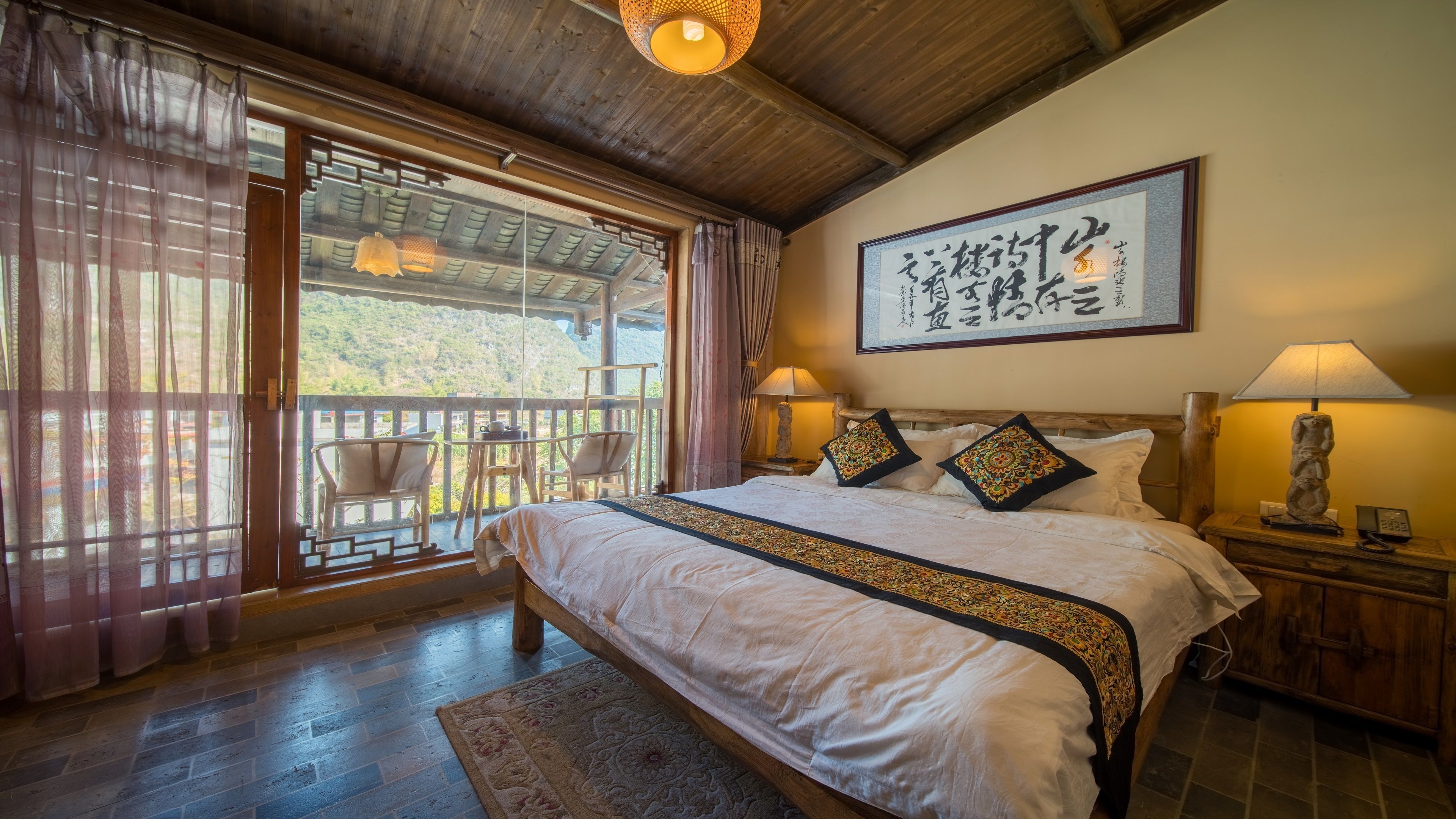 A bedroom with a large bed, wooden headboard, and a view of the outdoors through a sliding door.