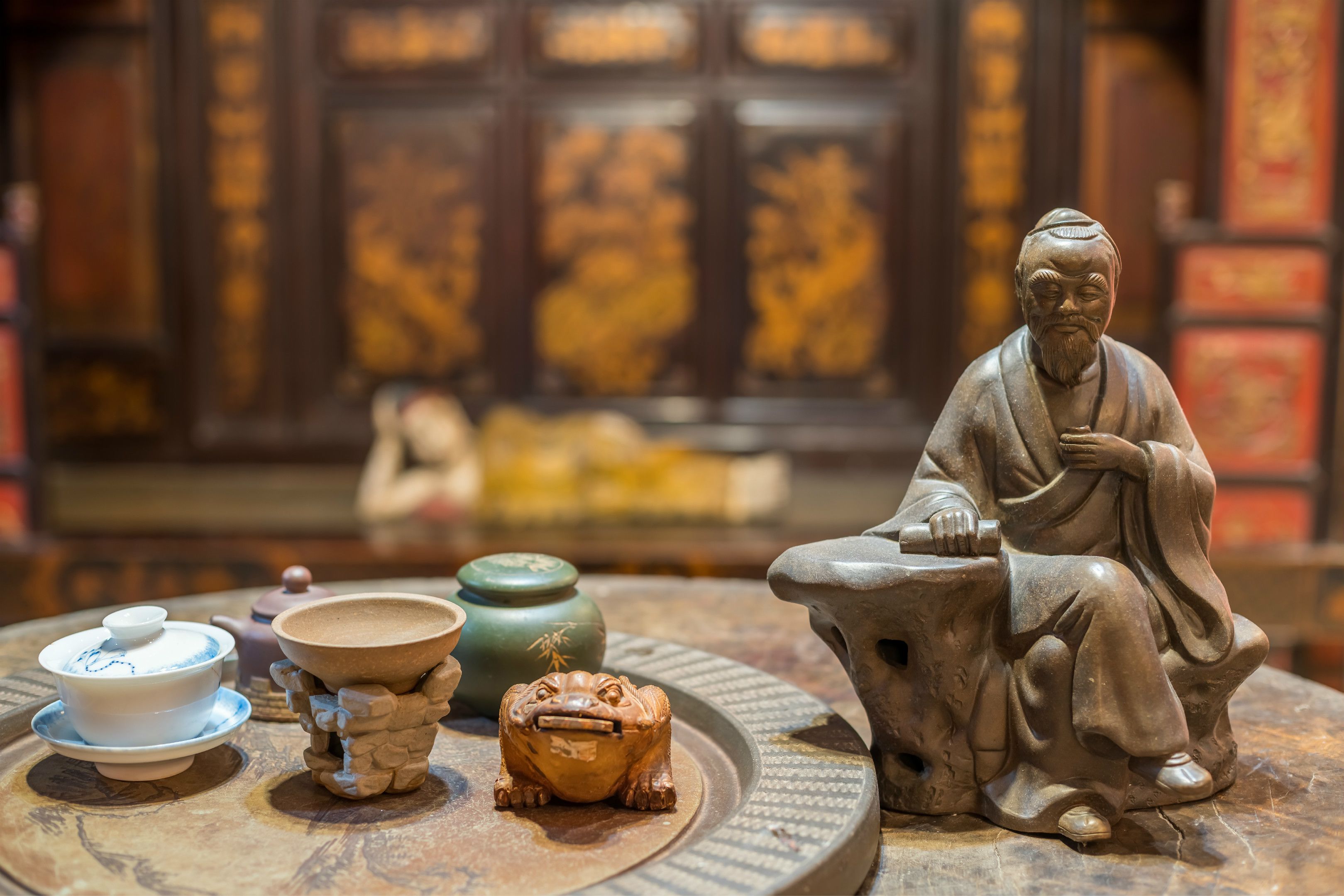 A traditional Chinese tea set with a teapot, cups, and a small frog figurine on a round table.