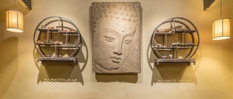A wall with a large stone sculpture and two circular shelves with decorative items.