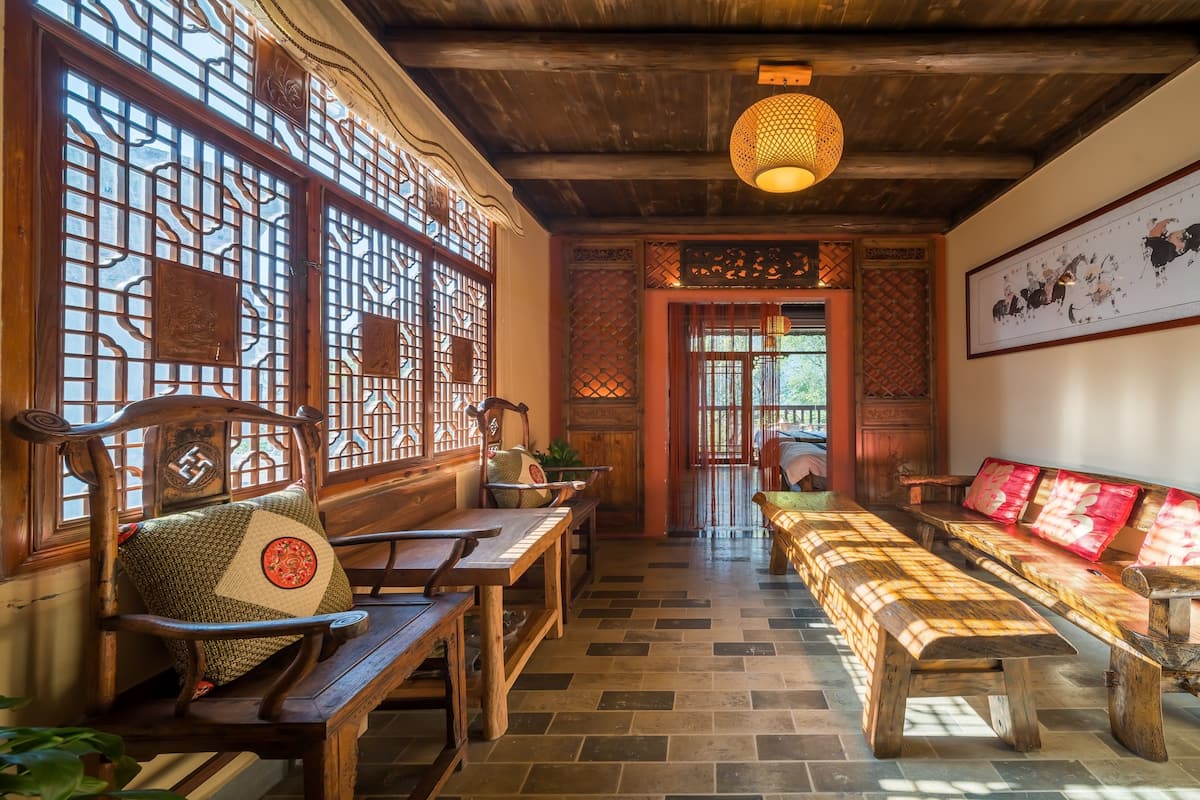 A traditional interior with wooden furniture, a patterned wall hanging, and a ceiling light fixture.