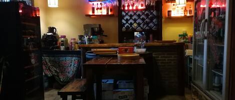 A bar area with a counter, stools, and a refrigerator.