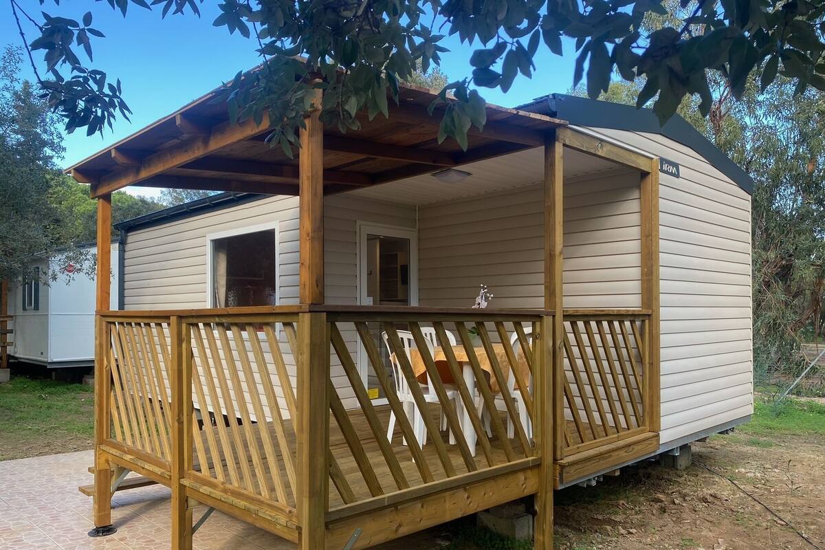 Ein Wohnmobil mit einer Holzdielen-Terrasse und einer überdachten Veranda.