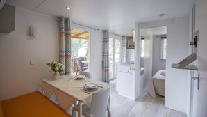 Een moderne keuken met witte kastjes, een eethoek met een tafel gedekt voor twee personen, en een klein zithoekje met een bank.
