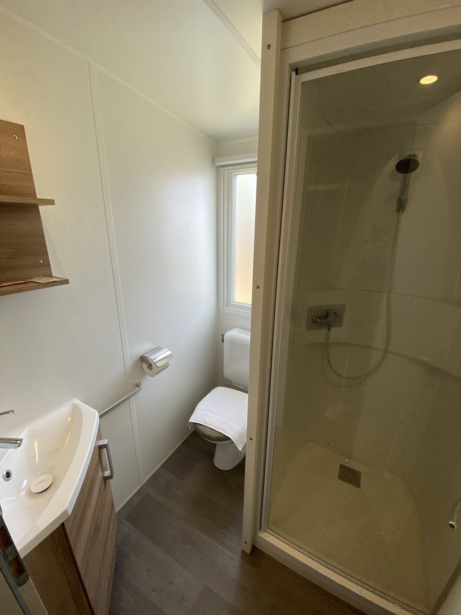 Un baño moderno con cabina de ducha de vidrio, un lavamanos blanco y un inodoro.