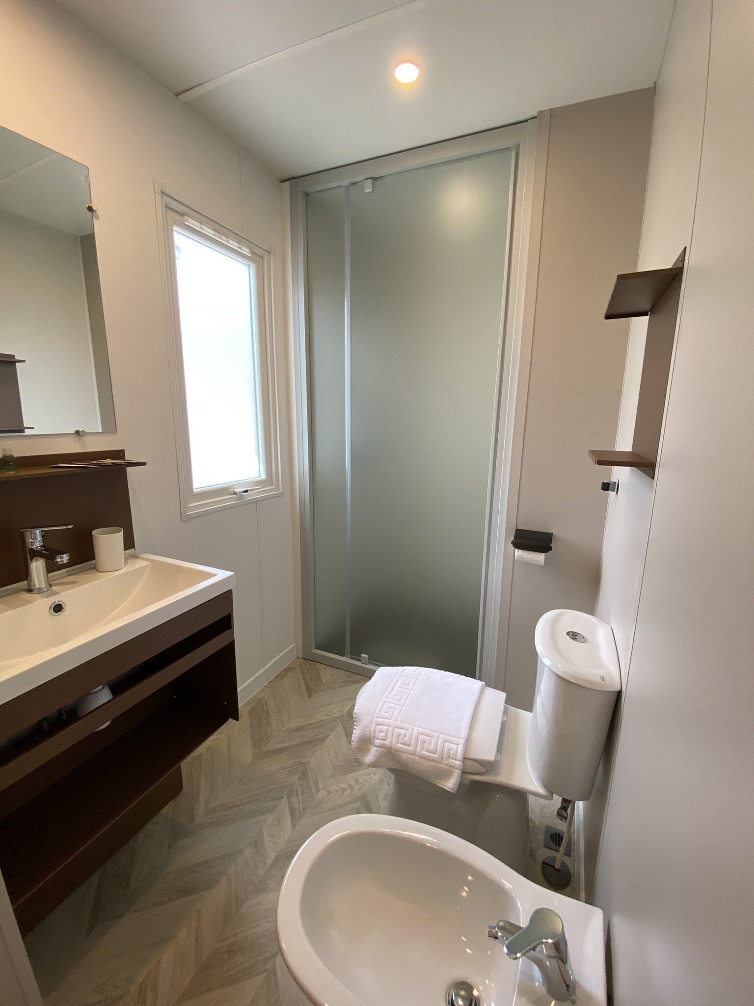 A modern bathroom with a sink, mirror, towel, and toilet.