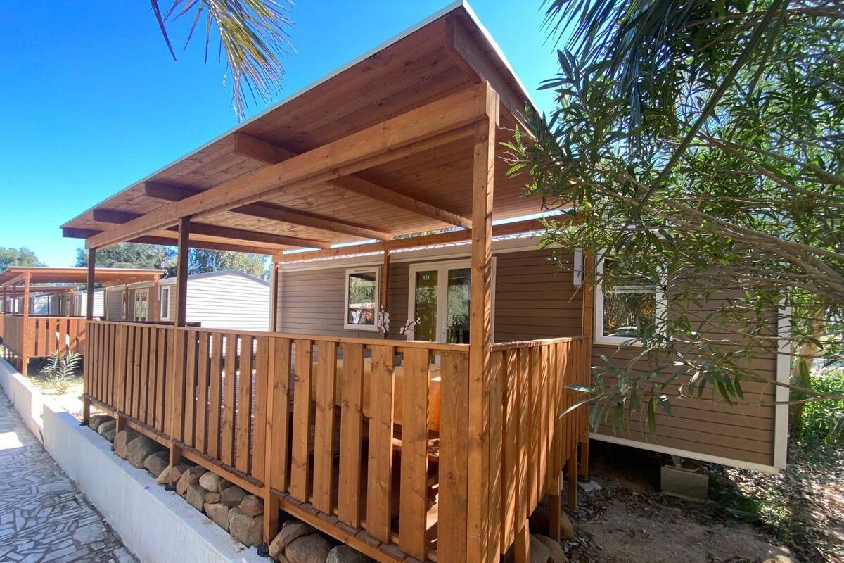 Eine Holzterrasse mit einer Pergola, umgeben von einer Steinmauer und einem Holzzaun.