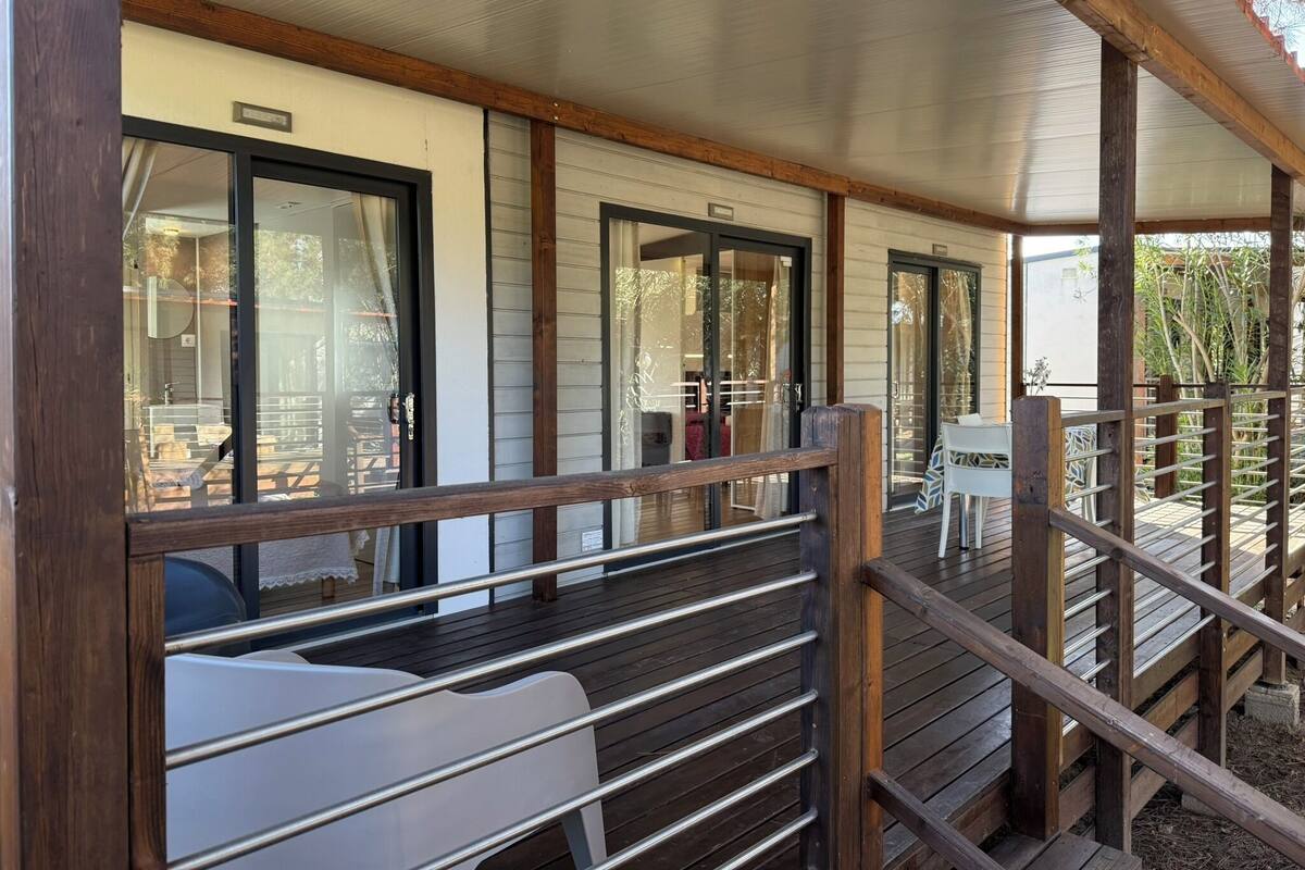 Eine überdachte Terrasse mit Holzgeländern und Blick ins Innere durch Glastüren.