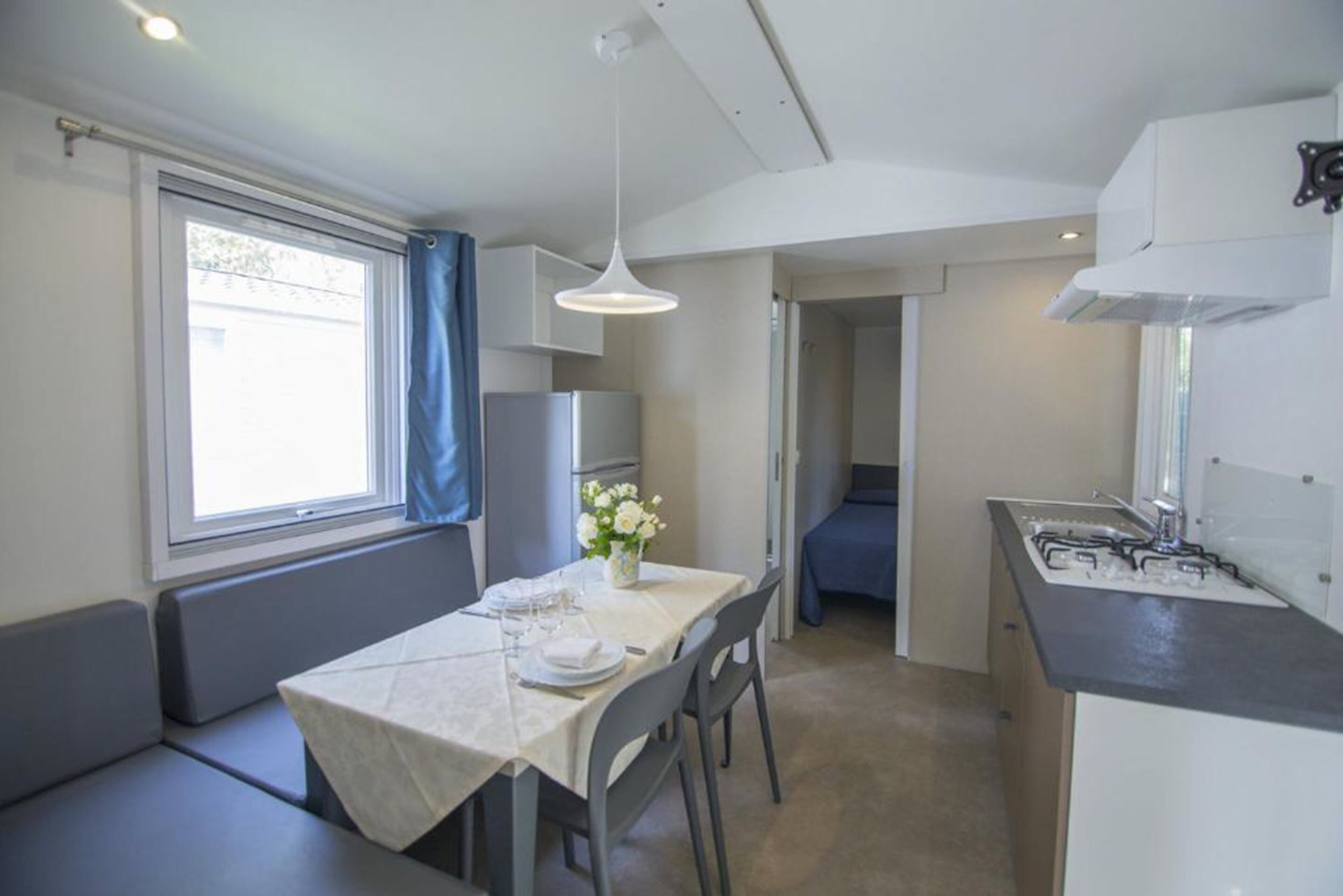 Una cocina compacta con zona de comedor, una ventana con cortinas y un lavamanos.