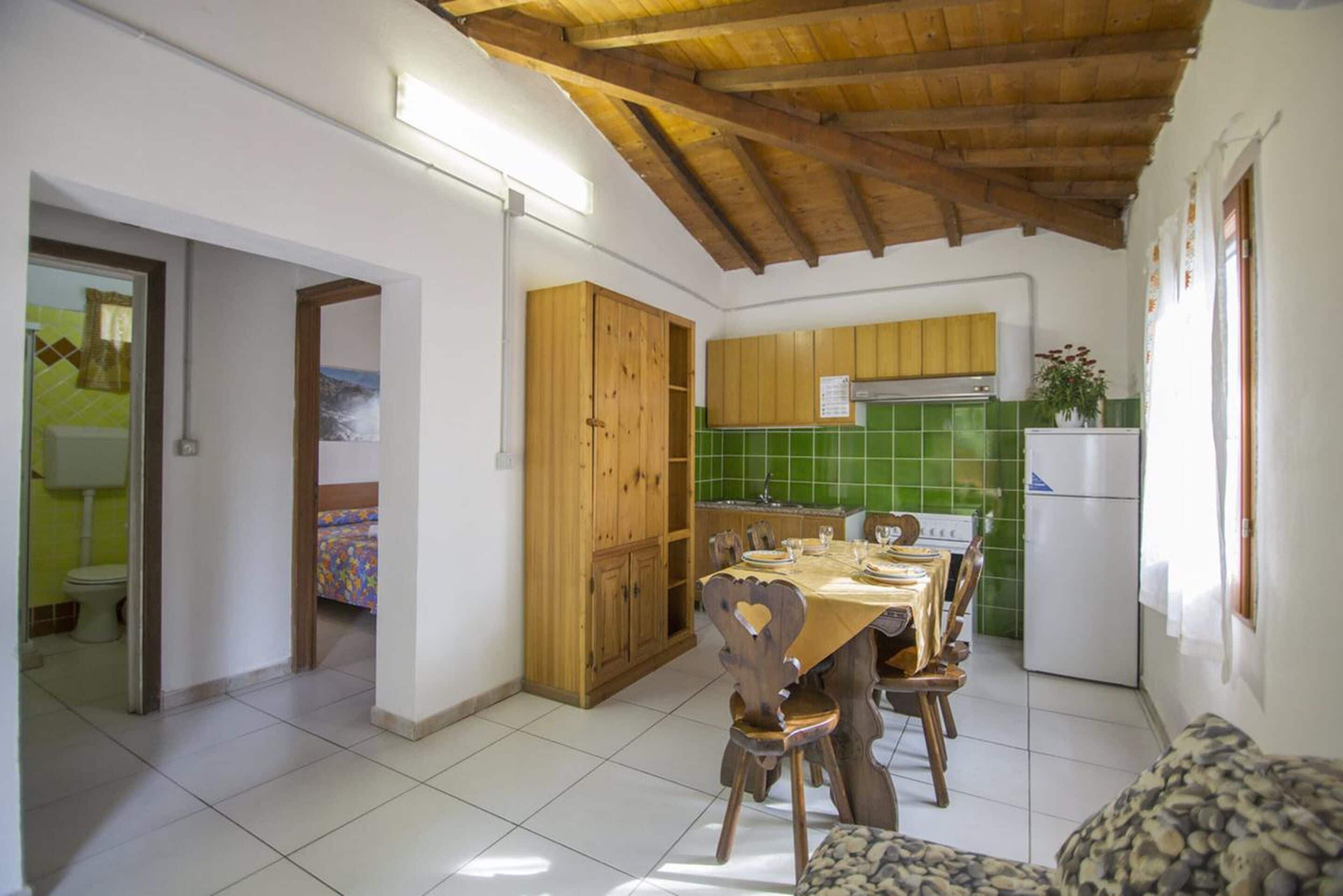 Una cocina con armarios de madera, una mesa de comedor para cuatro personas y un backsplash de azulejos verdes.