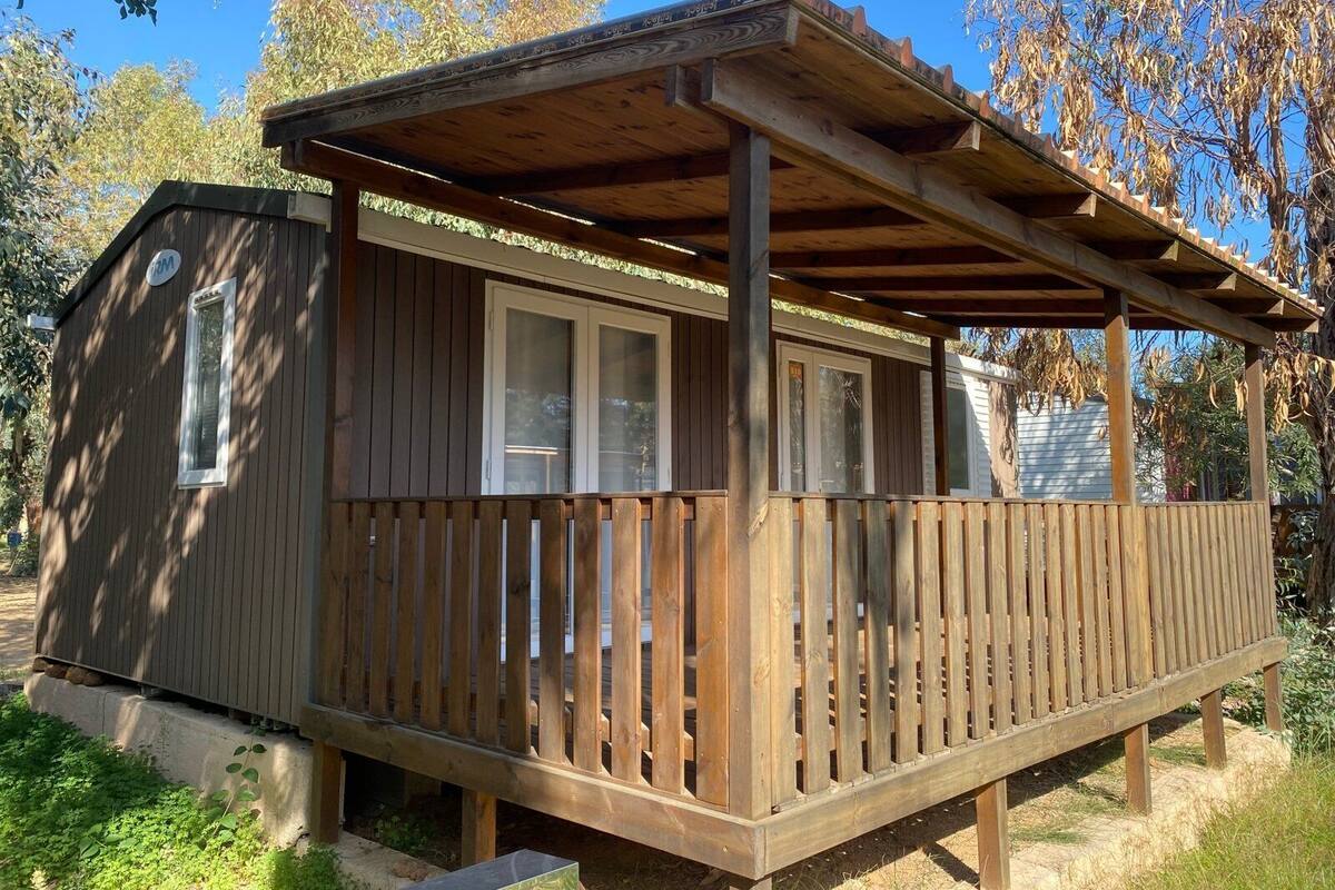 Eine Holzhütte mit überdachter Veranda und einem kleinen angebauten Schuppen.