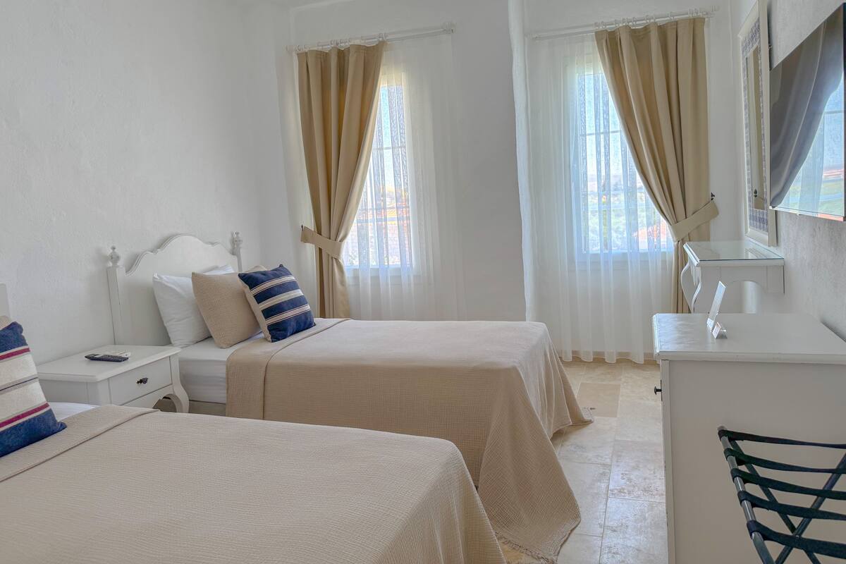 A hotel room with two beds, a bedside table, a desk, and a mirror.
