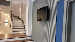A staircase with marble steps leading to a landing, a wall-mounted television, and a door with a blue panel. - Pendik Marine Hotel (Istanbul)