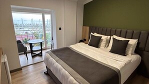 A modern bedroom with a large bed, a view of a marina, and a balcony with a table and chairs. - Pendik Marine Hotel (Istanbul)
