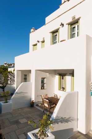 Un edificio blanco con un patio, una mesa de madera y plantas en macetas.