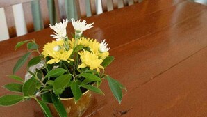 A wooden table with a vase of yellow and white flowers. - Pranee Beach Bungalows (Takua Pa)