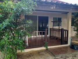 Un espacio de patio cubierto con barandilla de madera, una pequeña mesa y una planta en maceta.