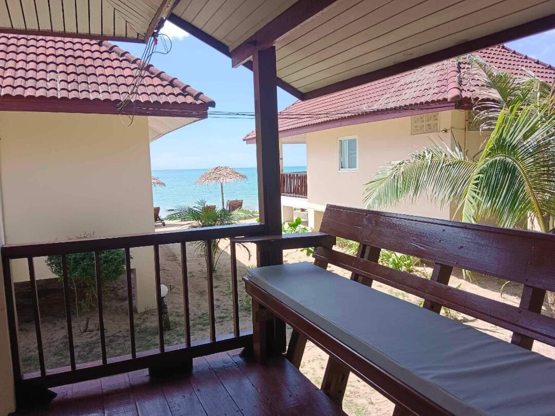 Un banco de madera en un porche cubierto con vistas a la playa.