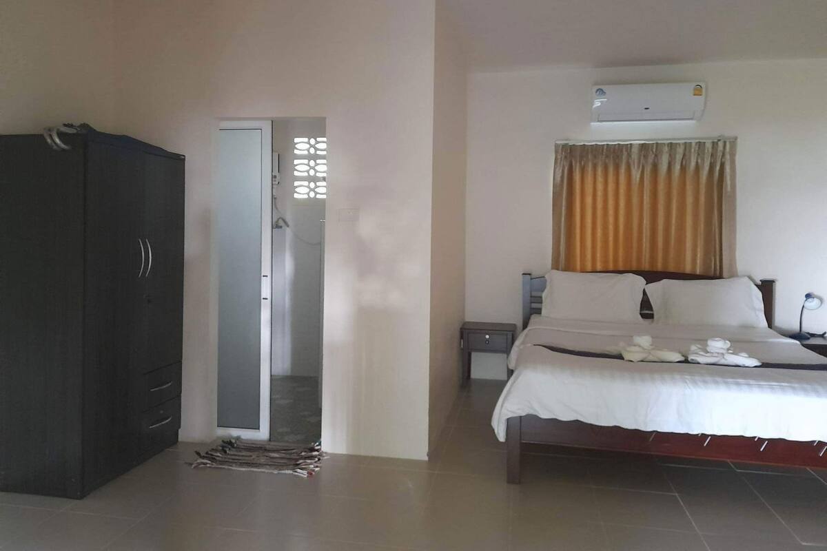 Quarto com cama, guarda-roupa, mesa de cabeceira e ar condicionado.