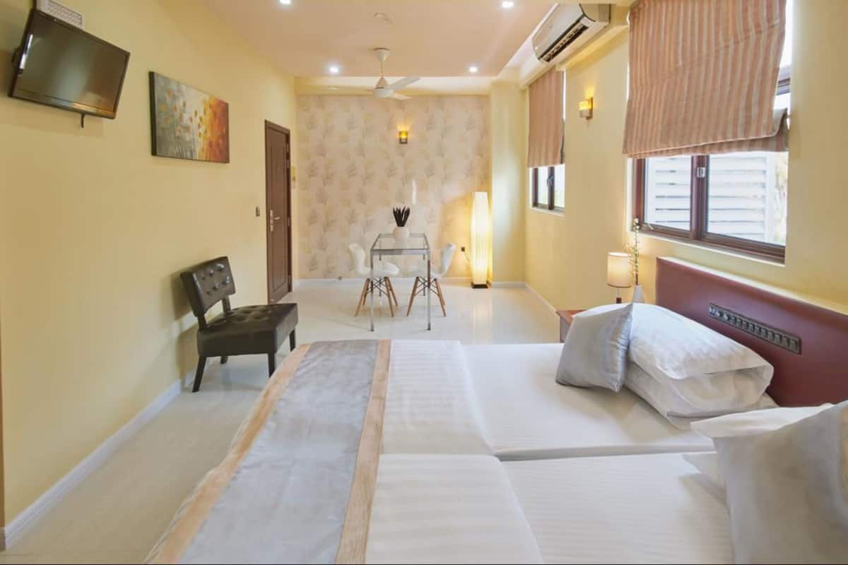 Habitación de hotel con cama, escritorio, silla, televisión y ventana con cortinas.