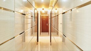 A modern, well-lit hallway with mirrored walls and a wooden door at the end. - Lonuveli (Hulhumalé)