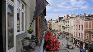 Ein Balkon mit einem Blumentopf, einem Stuhl und einer roten Blumenkomposition.