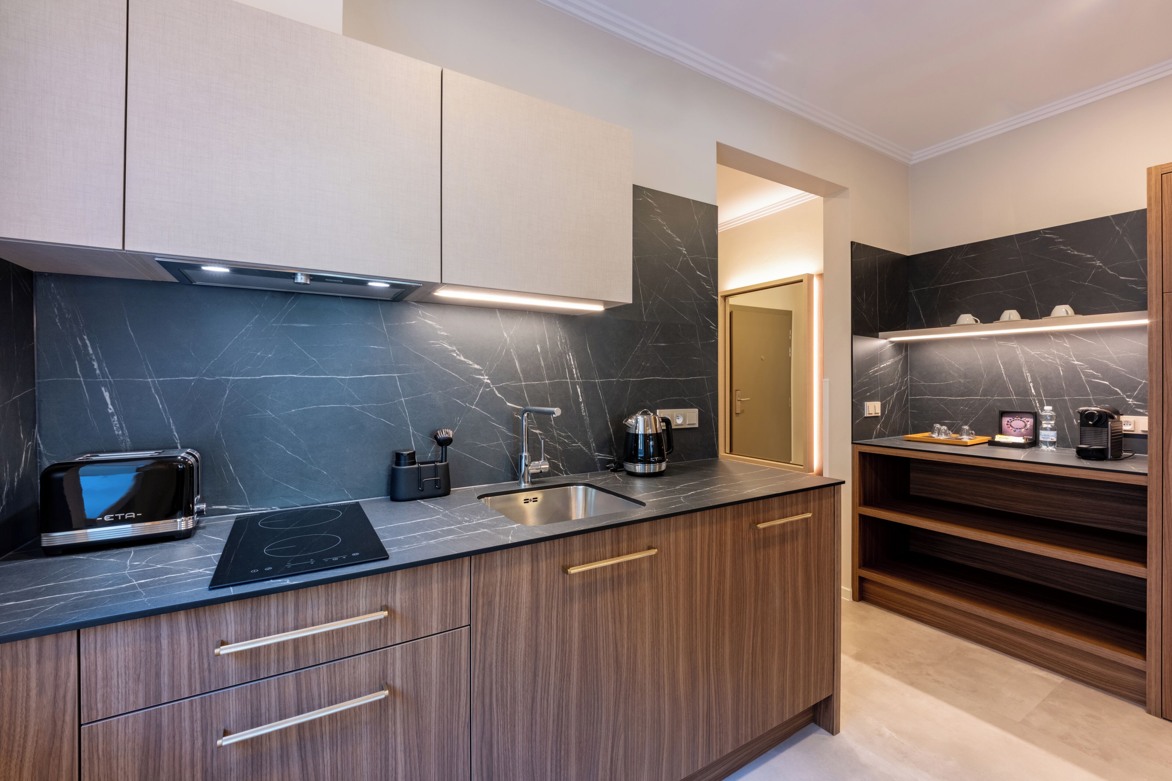 A modern kitchen with a black countertop, wooden cabinets, and a built-in oven.