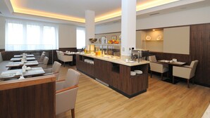 Ein modernes Restaurant mit einer zentralen Insellounge, verschiedenen Sitzbereichen und Holzboden.