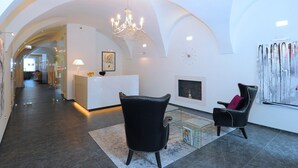 Ein modernes Interieur mit einer Rezeption, zwei schwarzen Sesseln, einer Kristallleuchtre und einem Kamin.