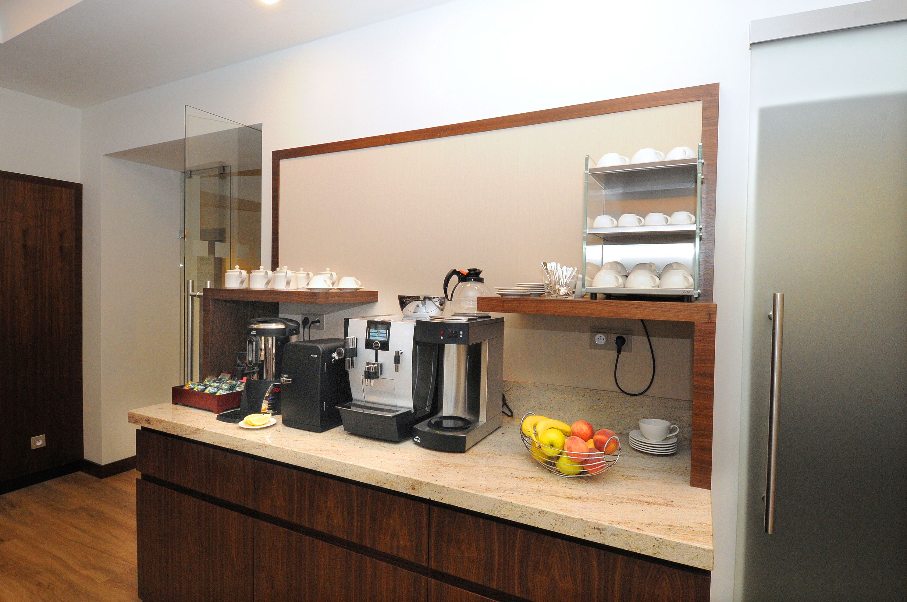 Una cocina moderna con espacio para café, un frutero y una vitrina de vidrio.