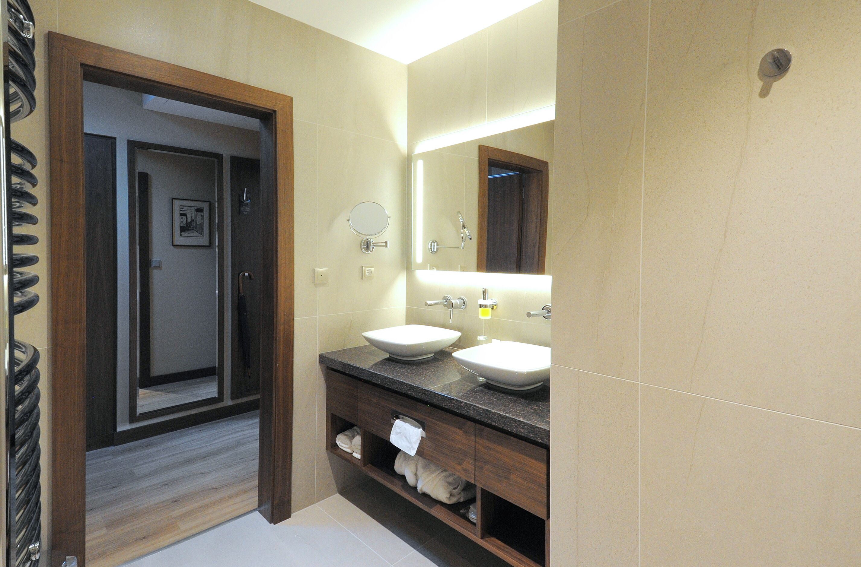 A bathroom with two sinks, a mirror, and a towel rack.