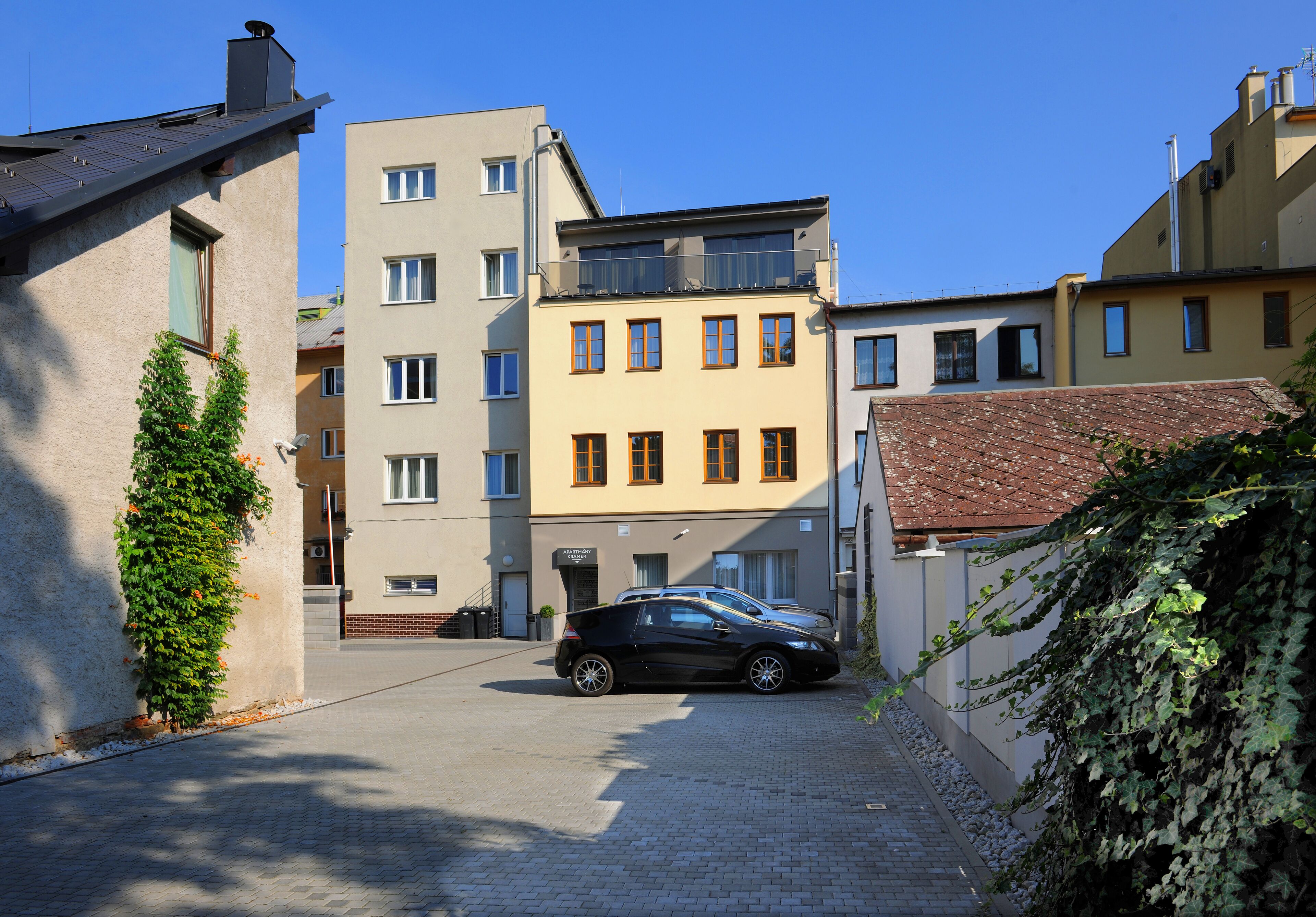 A building with a parking area and a black car parked in front.