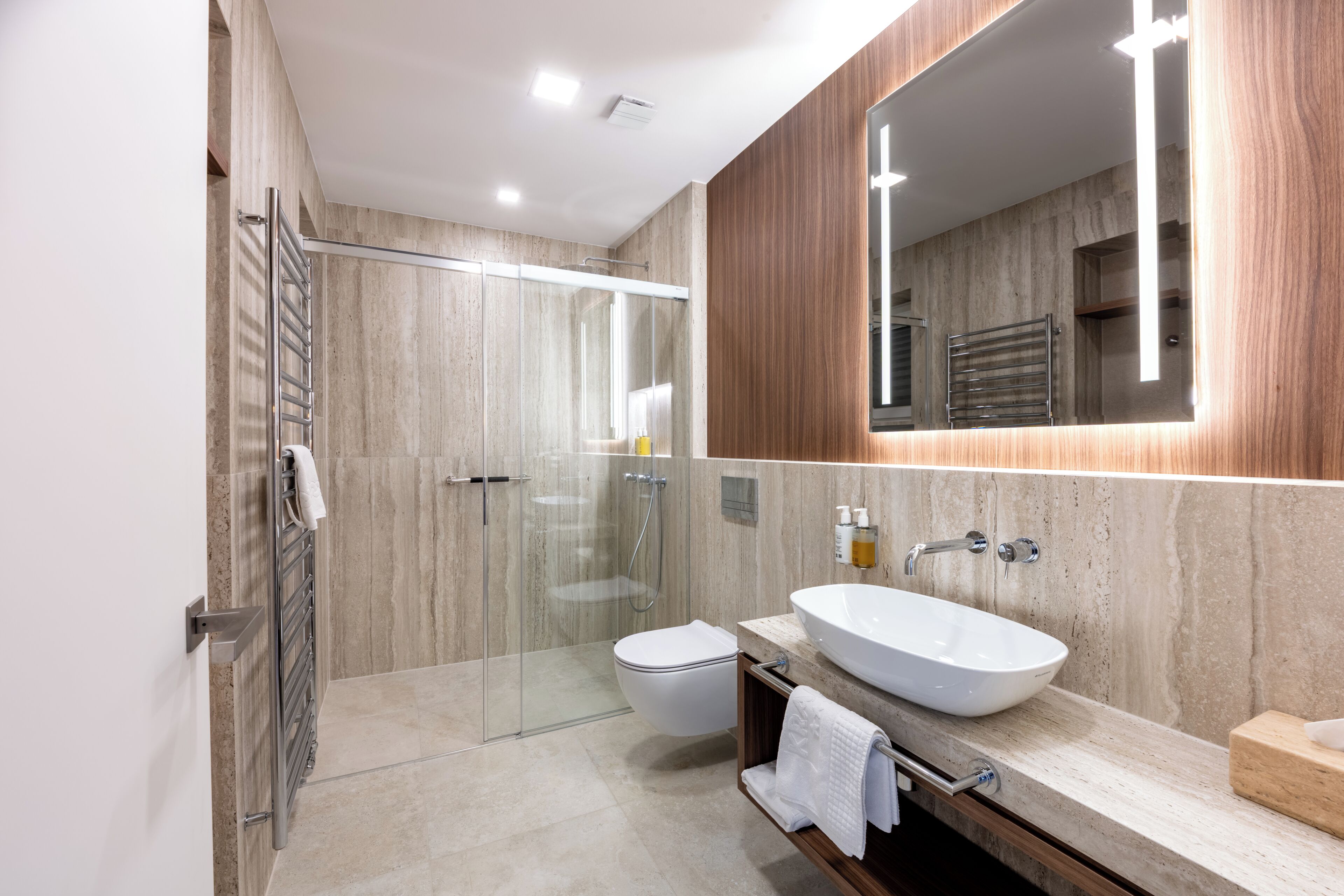 Un baño moderno con cabina de ducha de vidrio, inodoro independiente y un lavamanos grande tipo cuenco.