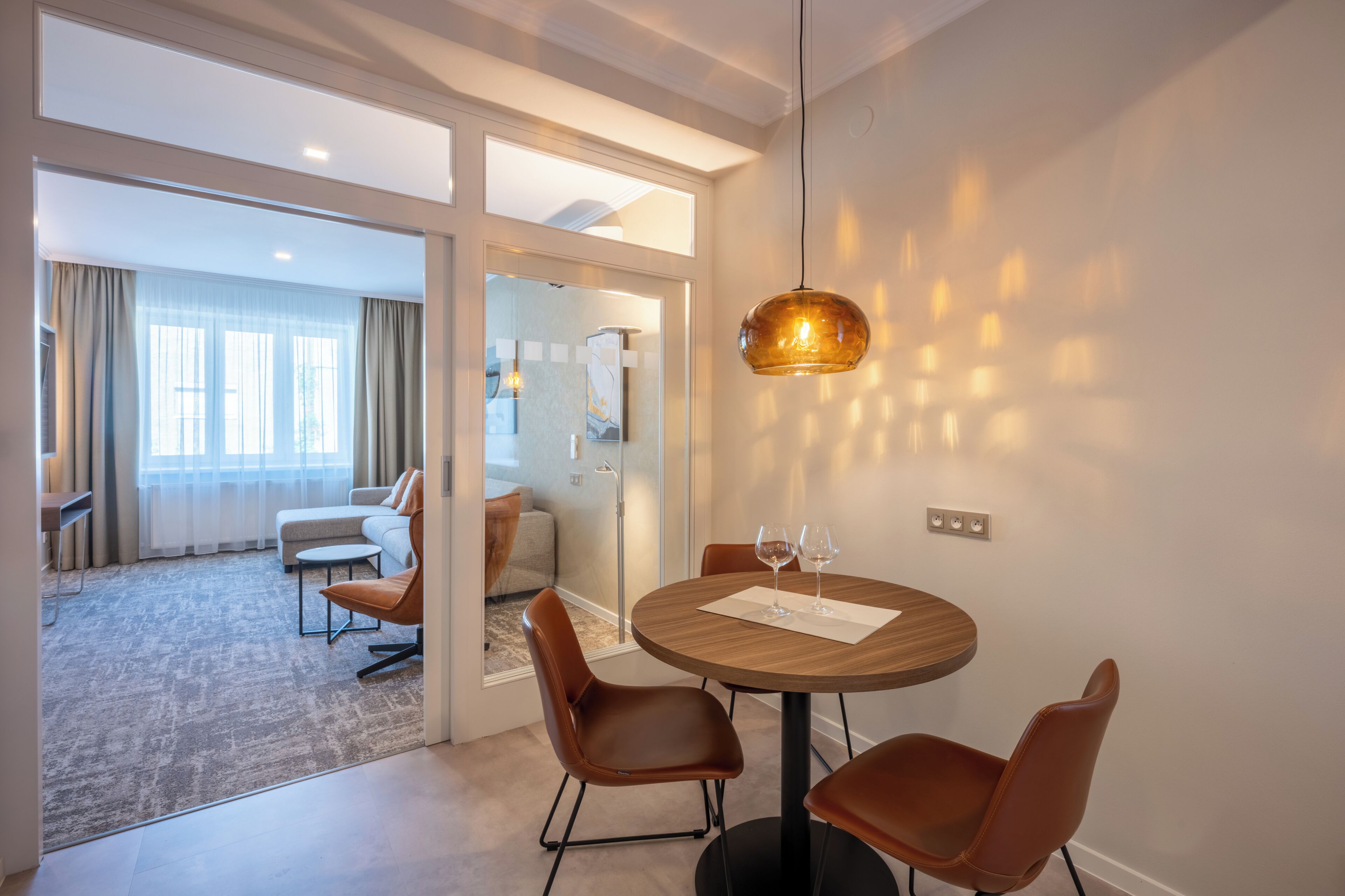 A modern dining area with a round table, four chairs, and a pendant light.