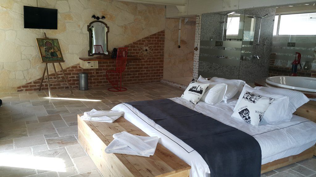 A bedroom with a large bed, a shower area, and a stone wall.