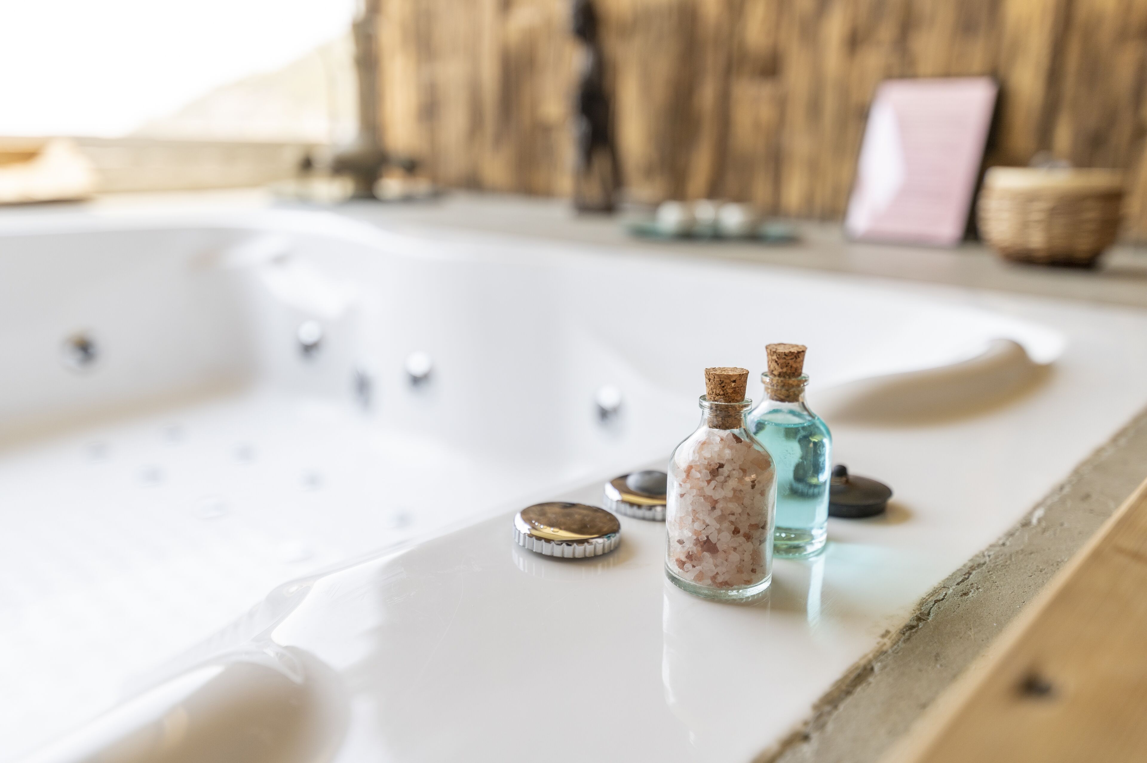 A bathtub with two bottles of bath salts and a bottle of blue liquid.