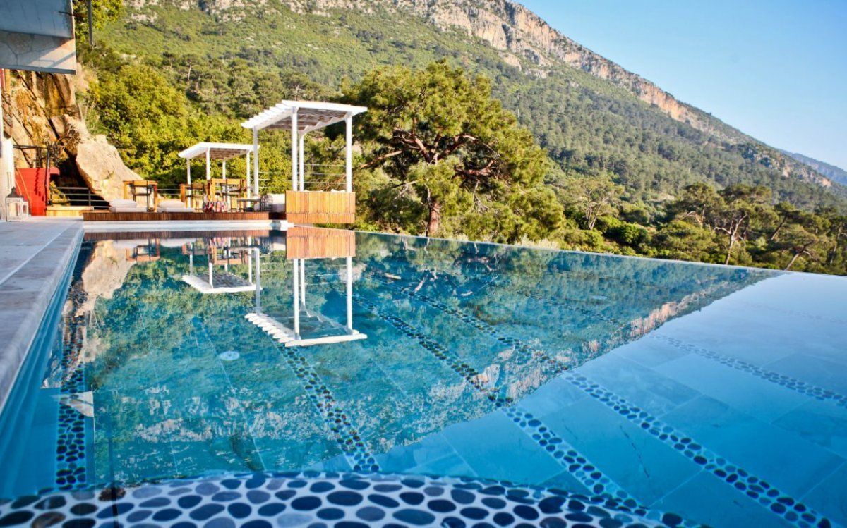 An infinity pool with a clear view of a mountainous landscape.