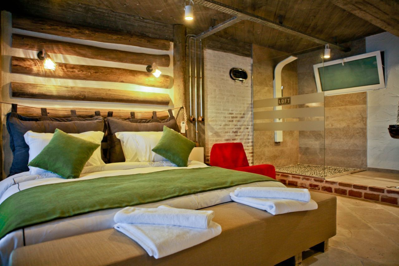 Ein Hotelzimmer mit Bett, Kissen, einem roten Sessel, einem Fernseher und einer Ziegelwand.