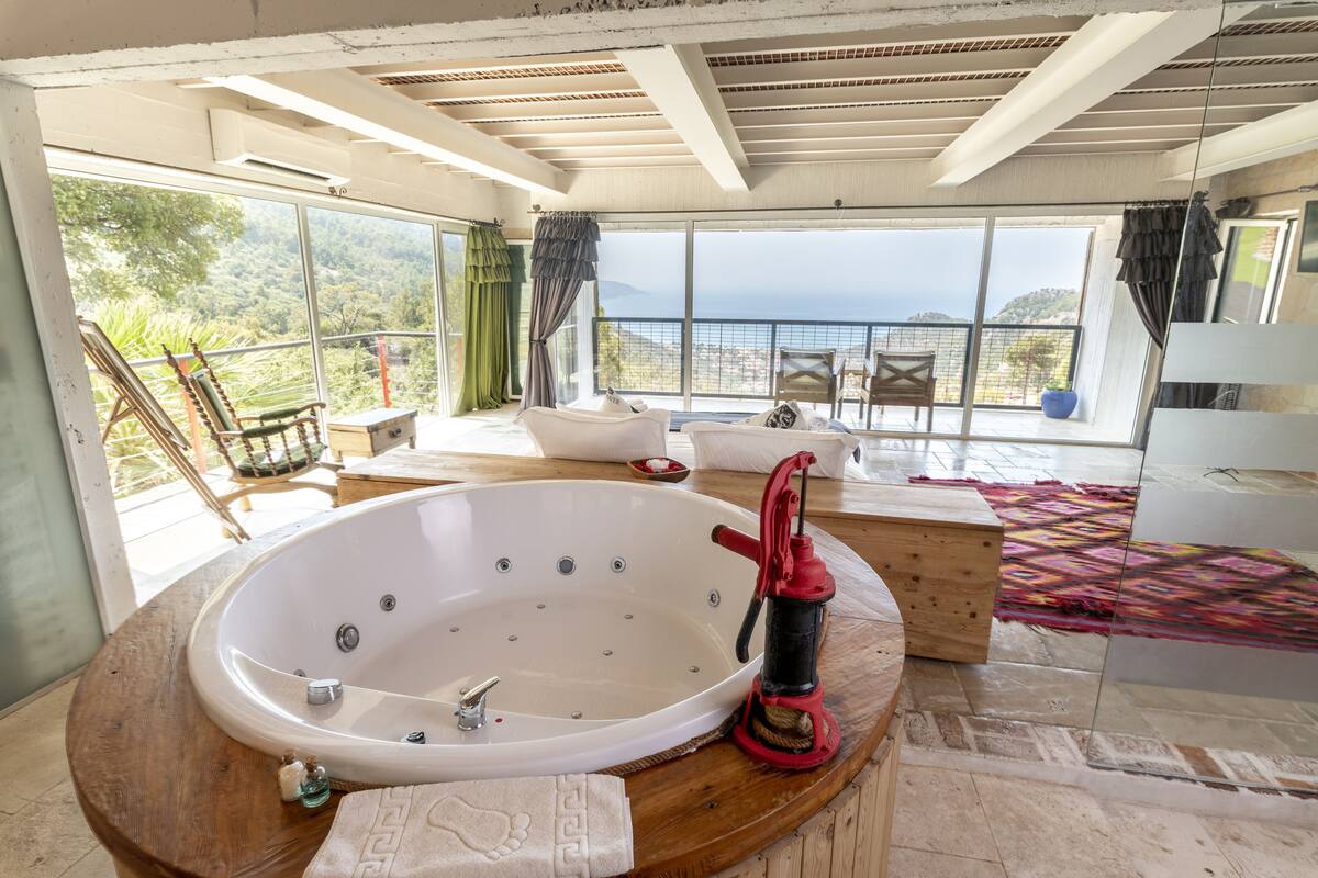 A spacious bathroom with a large bathtub, a wooden vanity, and a view of the outdoors.
