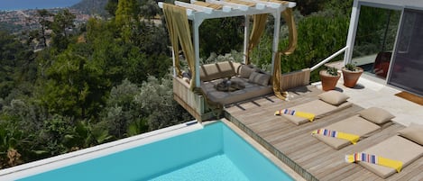 Una piscina al aire libre, sillones reclinables de piscina
