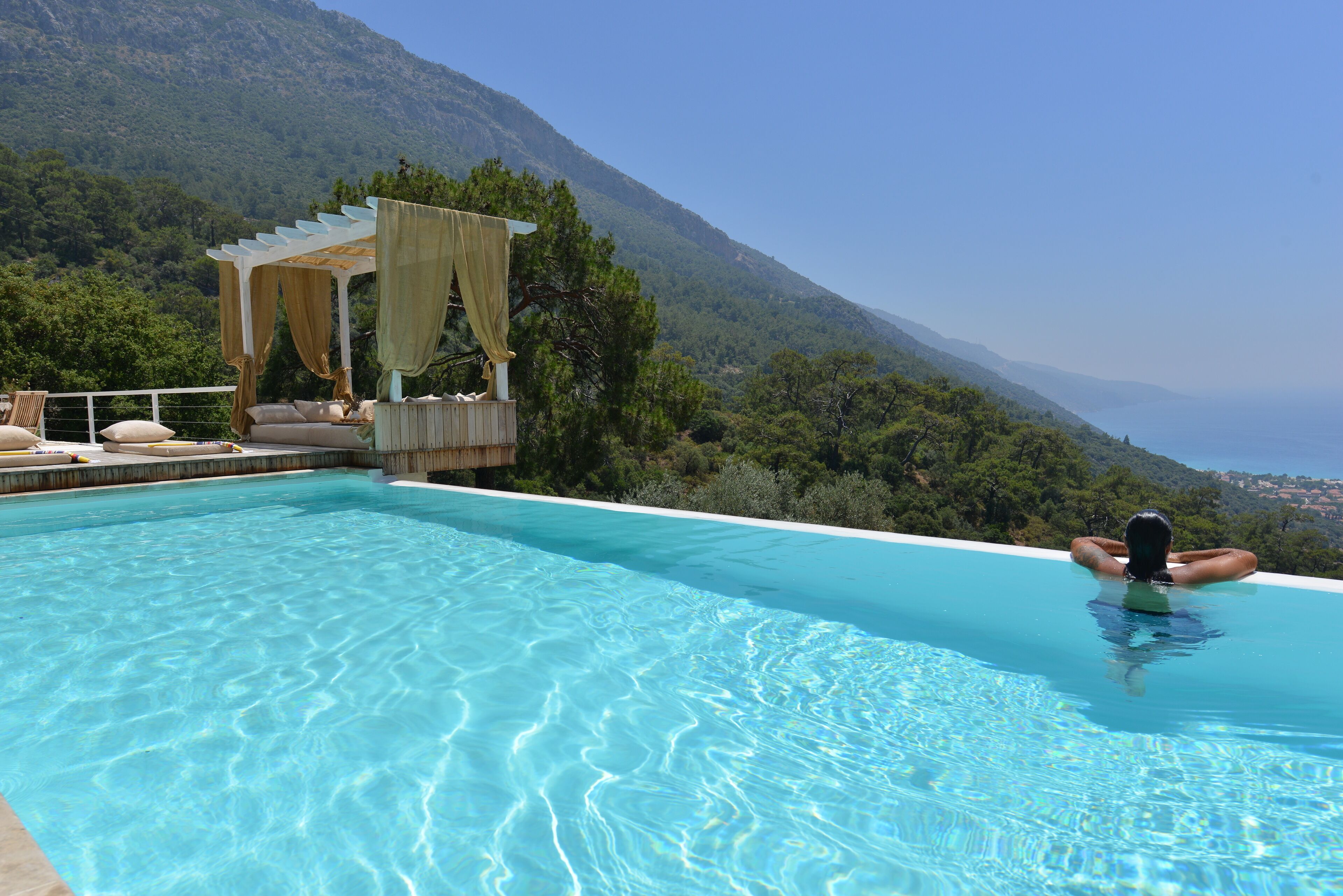 A swimming pool with a view of a mountain and the sea.