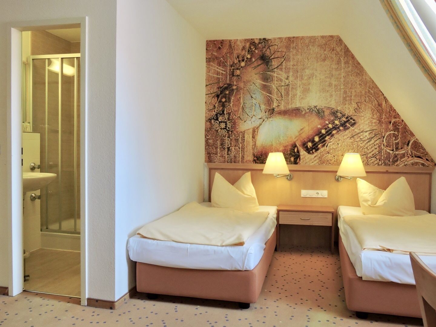 Habitación de hotel con dos camas, un cuadro abstracto grande en la pared y un baño visible a través de una puerta abierta.
