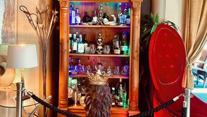 Una zona de bar con un estante de madera que muestra varias botellas y una estatua de un león con corona.