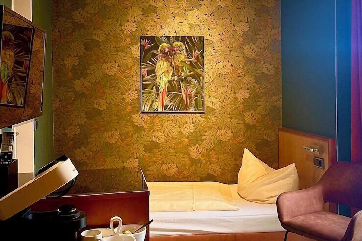 Ein Hotelzimmer mit Bett, Schreibtisch mit Lampe, Stuhl und einem Bild an der Wand.