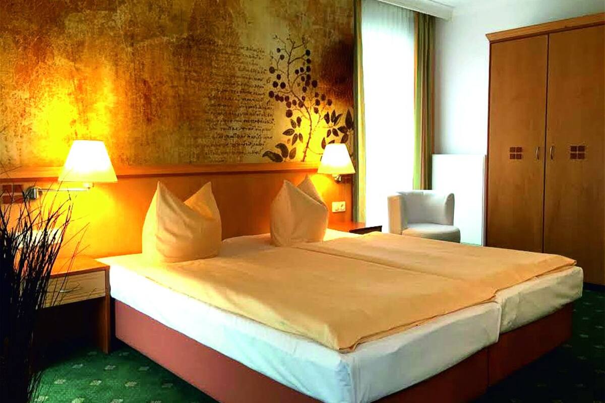 Ein Hotelzimmer mit einem großen Bett, zwei Nachttischlampen, einem Sessel und einem Kleiderschrank.