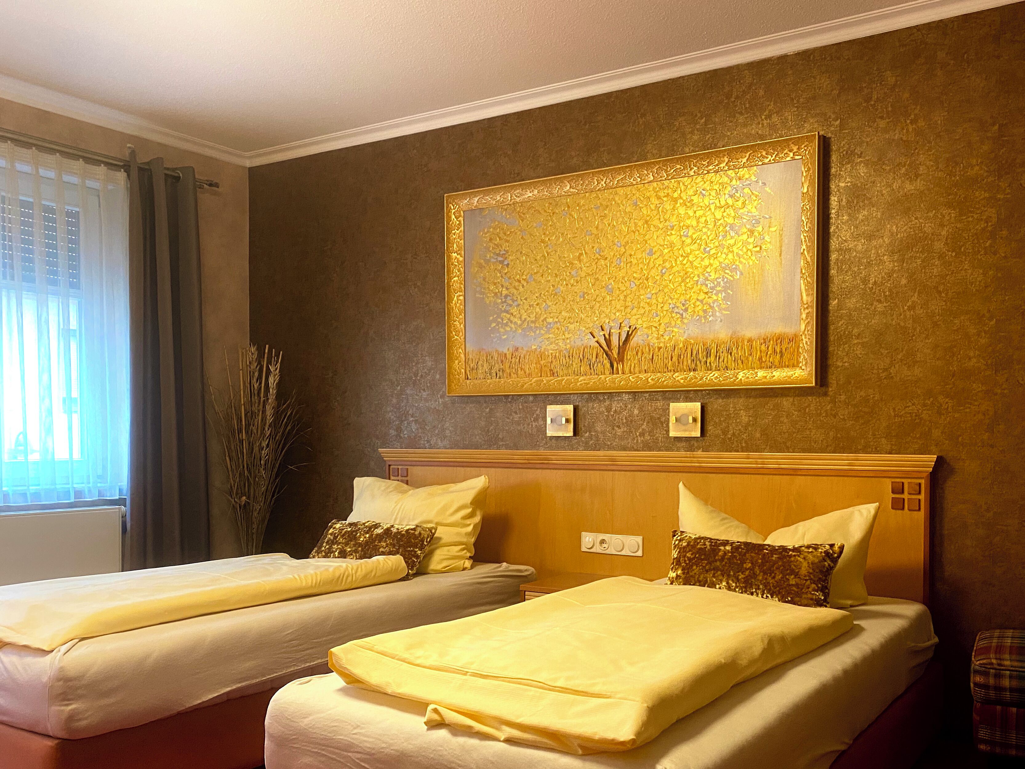 A hotel room with two beds, a large framed painting, and a window with curtains.